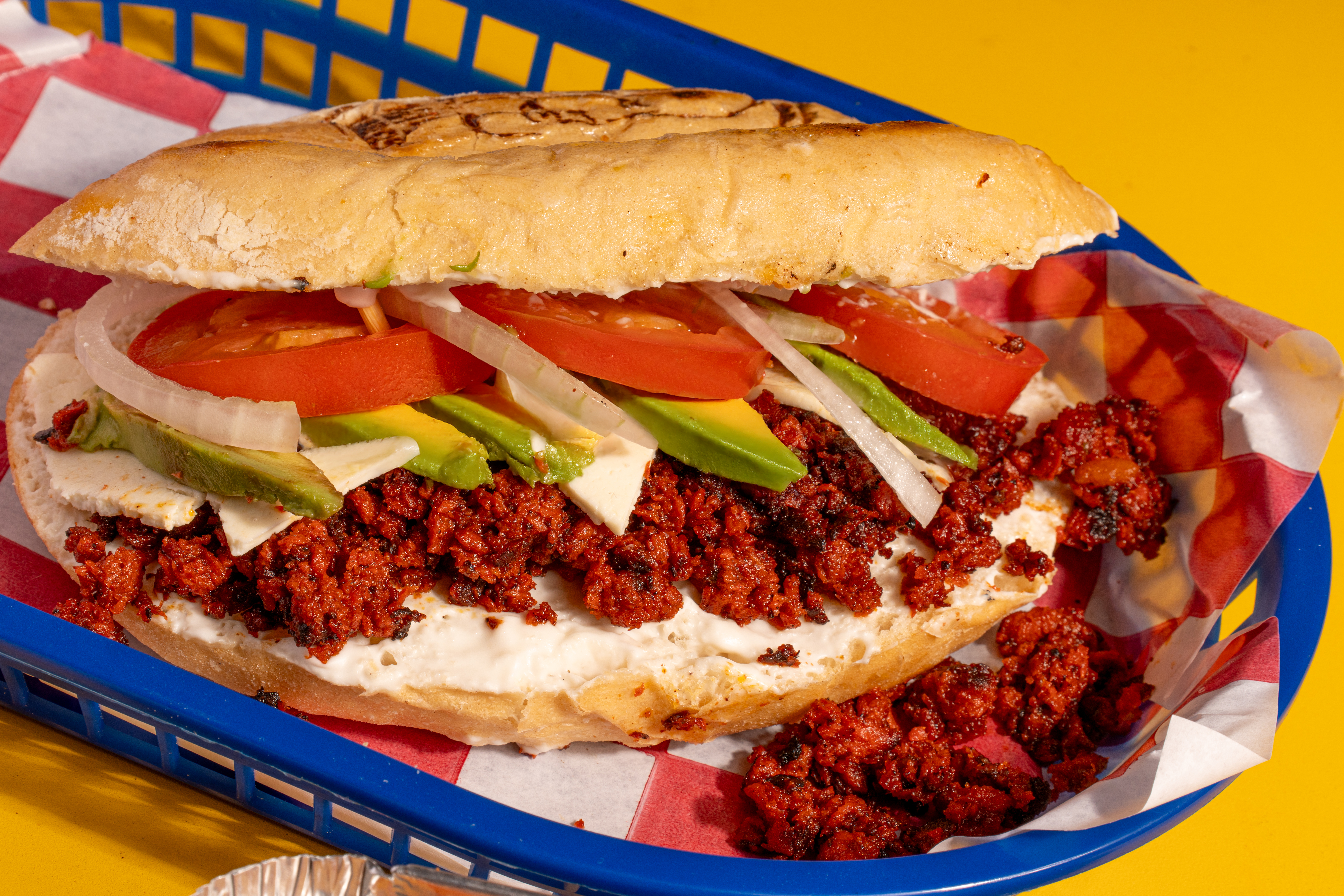 Torta con chorizo, cebolla, tomate, queso panela, aguacate, crema y chiles en vinagre, servida en pan crujiente