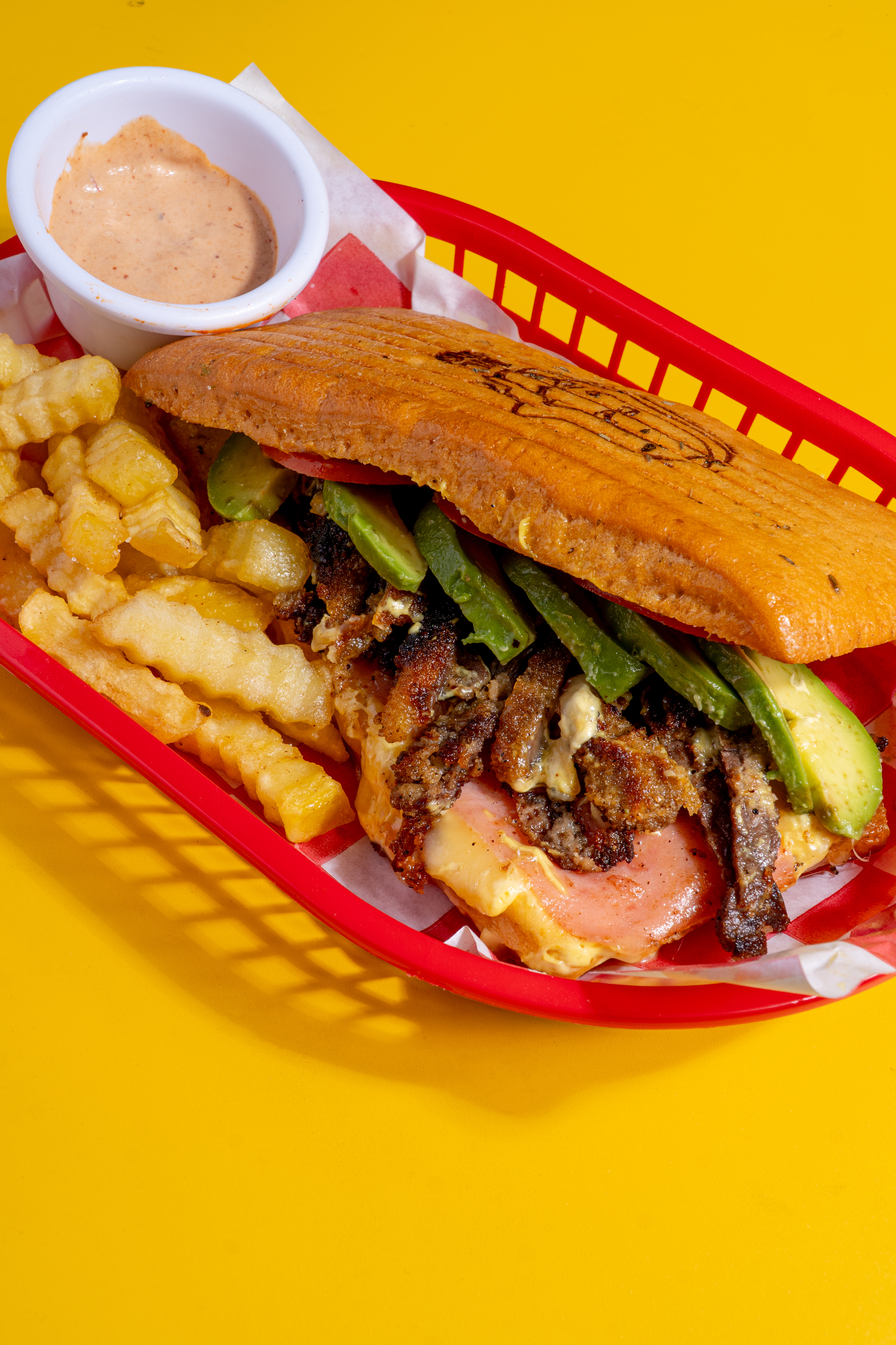 Combinación de sabores en un pan con milanesa de res jugosa, jamón de pavo, queso mozzarella, tomate y aguacate cremoso